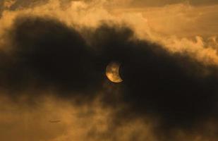 la luna cubriendo el sol en un eclipse parcial con nubes dramáticas. antecedentes científicos, fenómeno astronómico foto