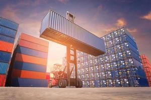 Forklift truck handling cargo shipping container box in logistic shipping yard with cargo container stack in background photo