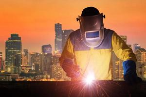 Industrial Worker with safety equipments and protective mask welding steel structure with modern cityscape in background. Elegant design for building and construction concept