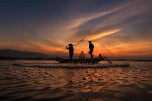 Pescador asiático con su bote de madera en el río de la naturaleza temprano en la mañana antes del amanecer foto