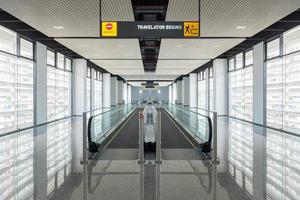 La pasarela moderna de la escalera mecánica avanza y la escalera mecánica se mueve hacia atrás en el aeropuerto internacional. La escalera mecánica es una instalación para el transporte de apoyo en un edificio moderno. foto