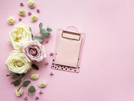 Clipboard and flowers on pink background photo