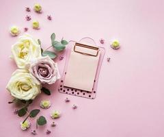 Clipboard and flowers on pink background photo