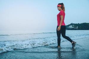 Woman jogging workout on the beach in the morning. Relax with the sea walk. in summer photo