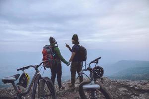 Asian lover women and men Travel Nature. Travel relax ride a bike Wilderness in the wild. Standing on a rocky cliff. Thailand photo