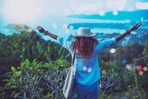 mujer viajar relajarse la playa brazos levantados feliz contra la puesta de sol. en verano foto