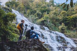 Asian couple travel nature. Travel relax. Stand landscapes Natural Touch Stand to see beautiful waterfalls mae ya at Chiangmai in Thailand photo