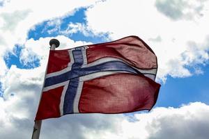 La bandera nacional de Noruega en el cielo azul de viento áspero. foto