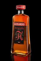 Italian liqueur Amaretto on black background with reflection. photo