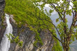 Highest freefall waterfall Vettisfossen behind trees Utladalen Norway norwegian landscapes. photo
