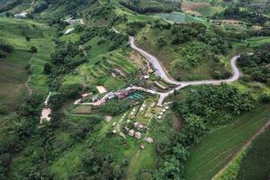 Aerial view of hut resort on hillside among the mountain in tropical rainforest on rainy day photo