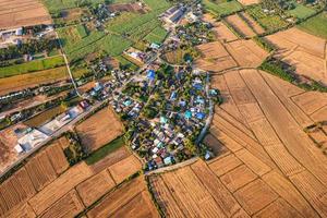 Pueblo suburbano entre arrozales cosechados con vía en campo foto