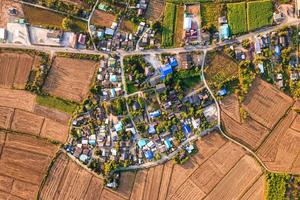 Pueblo suburbano entre arrozales cosechados con vía en campo foto