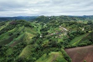 Aerial view of hut resort on hillside among the mountain in tropical rainforest on rainy day photo