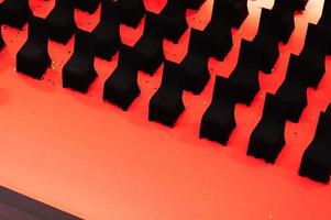 Row of empty black chairs on red floor in performance stage photo