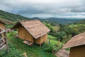 Wooden thatched hut resort on hill among mountain in tropical rainforest photo