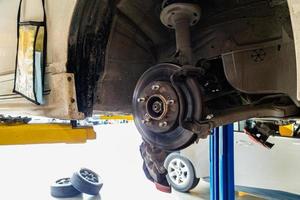 Damaged car and dirty disc brake lifting for maintenance in workshop photo