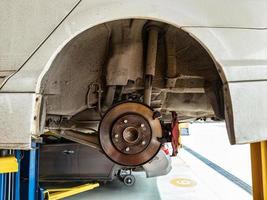 Damaged car and dirty disc brake lifting for maintenance in workshop photo