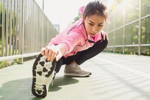 Fitness sport girl fashion sportswear doing yoga fitness exercise in street. Fit young asian woman doing training workout in morning. Young happy asian woman stretching at park after running workout. photo
