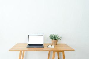 Front view of creative designer desktop with mockup copy space white laptop screen, supplies and other items on desk. Stylish workspace concept. photo