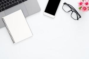 Creative flat lay photo of workspace desk. Top view office desk with laptop, glasses, phone, notebook and plant on white color background. Top view with copy space, flat lay photography.