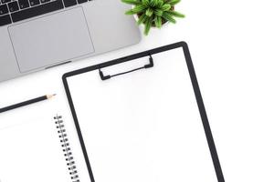 Creative flat lay photo of workspace desk. Top view office desk with laptop, pencil, blank clipboard and plant on white color background. Top view with copy space, flat lay photography.