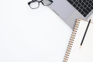 Creative flat lay photo of workspace desk. Top view office desk with laptop, glasses, pencil, notebook and plant on white color background. Top view with copy space, flat lay photography.