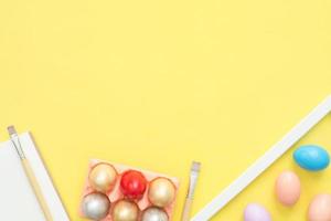 Flat lay top view colorful easter egg painted in pastel colors composition with paint brush on yellow pastel color background. Easter day background top view with copy space. photo