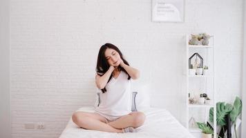 hermosa mujer asiática estirando su cuerpo después de despertarse en su habitación en casa. mujer feliz disfruta de la mañana soleada. mujer de estilo de vida en el concepto de hogar. foto