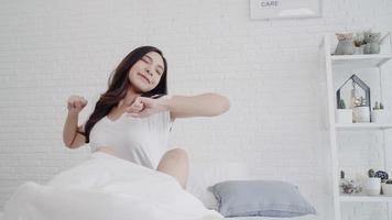 Beautiful Asian woman stretching her body after she wake up in her bedroom at home. Happy female enjoy sunny morning. Lifestyle woman at home concept. photo