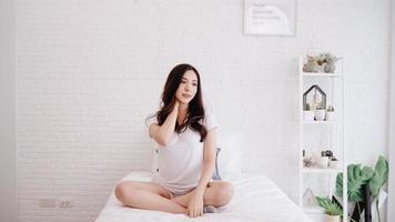 Beautiful Asian woman stretching her body after she wake up in her bedroom at home. Happy female enjoy sunny morning. Lifestyle woman at home concept. photo