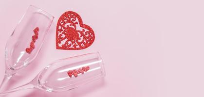 Two glasses and hearts on a pink background - romantic date for Valentine's Day concept in banner format photo
