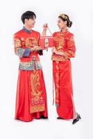 hombres y mujeres vistiendo cheongsam de pie con bolsas rojas foto