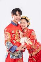 The man and woman wear Cheongsam with showing red gift money from family in traditional day photo