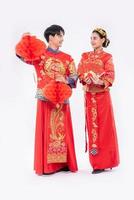 el hombre y la mujer usan cheongsam sonriendo para obtener una bonita lámpara roja y dinero de regalo foto