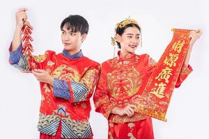 Man and woman wear Cheongsam suit promote chinese greeting card and firecracker to use in chinese new year photo