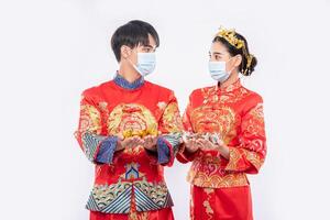 Men and women wearing Qipao and wearing masks Spend with gold money photo