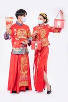 hombres y mujeres usan cheongsam bienvenidos: obtenga dinero de regalo y una bolsa roja para el día tradicional foto