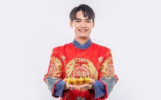 hombre vestido con traje cheongsam regalar oro a su pariente por suerte en el año nuevo chino foto