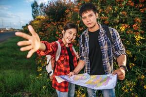 Both male and female tourists carry a backpack standing at a flower garden. photo