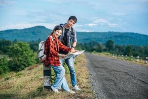 Male and female tourists standing look at the roadside map. photo