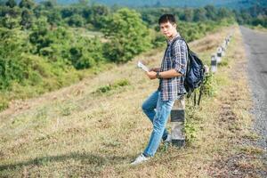 Male traveler with a backpack Holding a map and standing near to a kilometer. photo