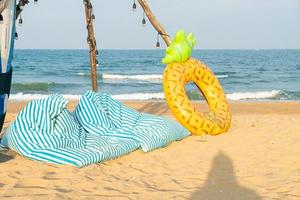 bean bag and ring pool on beach with sea background photo
