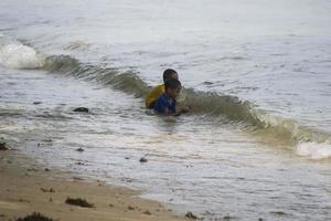Sorong, West Papua, Indonesia, December 12th 2021. Boys playing against the waves on the beach