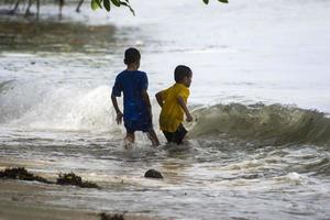 Sorong, West Papua, Indonesia, December 12th 2021. Boys playing against the waves on the beach