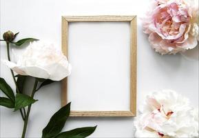 Wooden frame surrounded by beautiful pink peonies on a white background photo