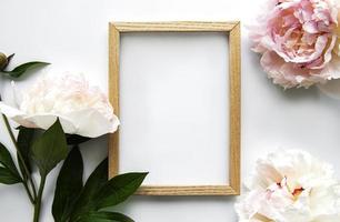 Wooden frame surrounded by beautiful pink peonies on a white background photo