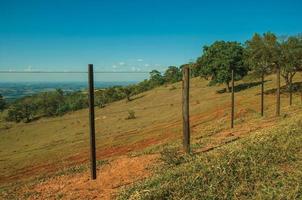 pardinho, brasil - 31 de mayo de 2018. vista de prados y árboles en un valle verde y cerca de alambre de púas, en un día soleado cerca de pardinho. un pequeño pueblo rural en el campo del estado de sao paulo. foto
