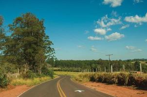 pardinho, brasil - 31 de mayo de 2018. camino pavimentado de campo en un paisaje montañoso cubierto por prados y árboles, en un día soleado cerca de pardinho. un pequeño pueblo rural en el campo del estado de sao paulo. foto