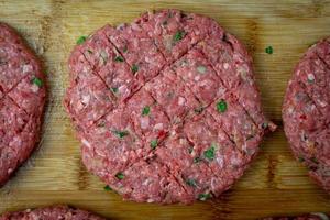 Raw beef prepared for burgers. Seasoned meat on a wooden board. Top view. photo